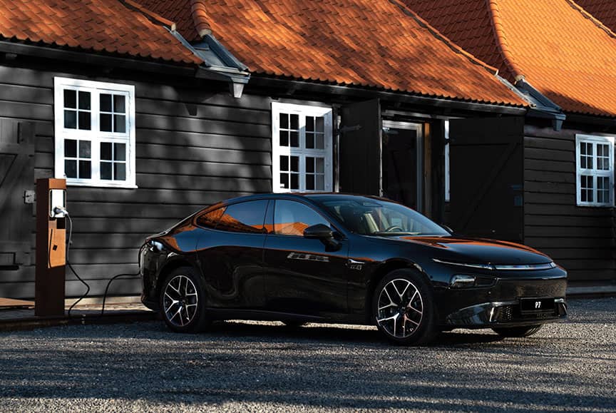 אקספנג P7 בחניה מחובר לעמדת טעינה לצד בתים בסביבה כפרית אירופית