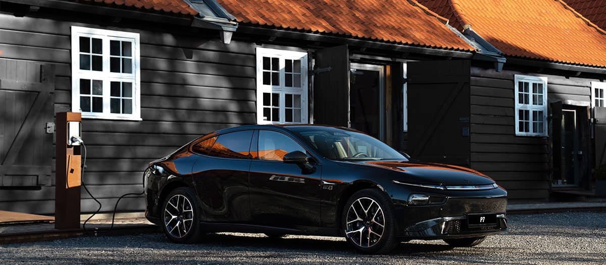 אקספנג P7 בחניה מחובר לעמדת טעינה לצד בתים בסביבה כפרית אירופית