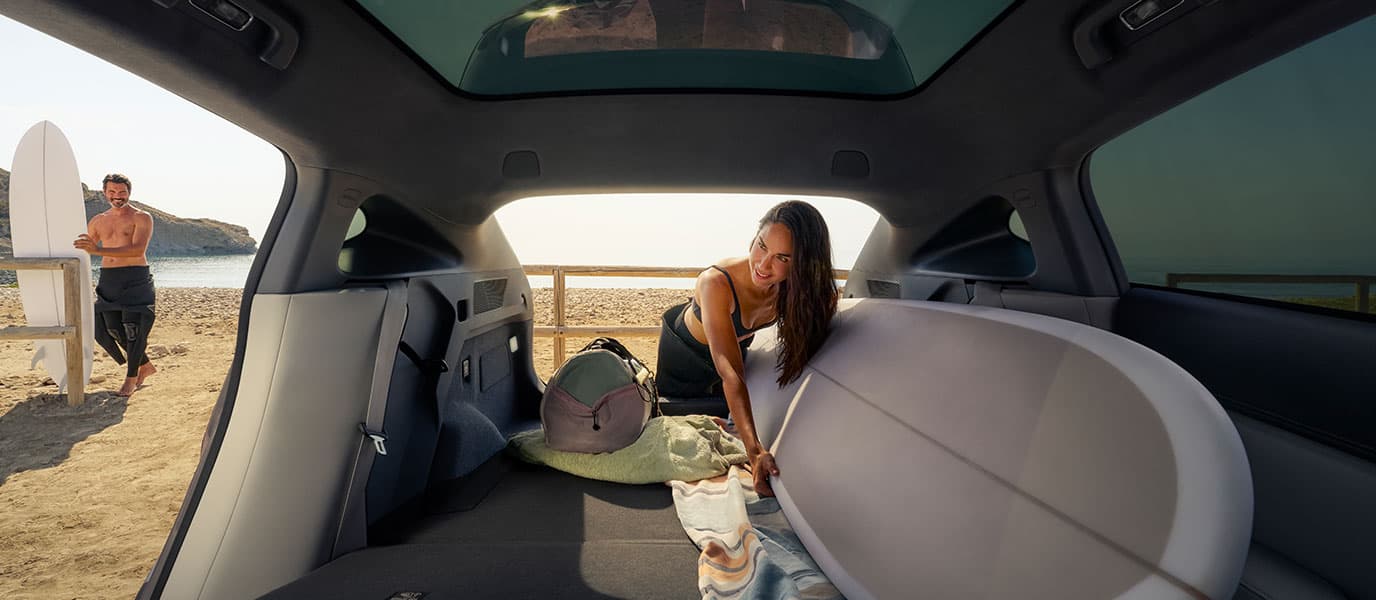 אישה מעמיסה את תא המטען של אקספנג G6 בציוד גלישה