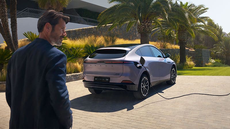 גבר עומד מאחורי מכונית אקספנג G6 סגולה מחוברת לעמדת טעינה